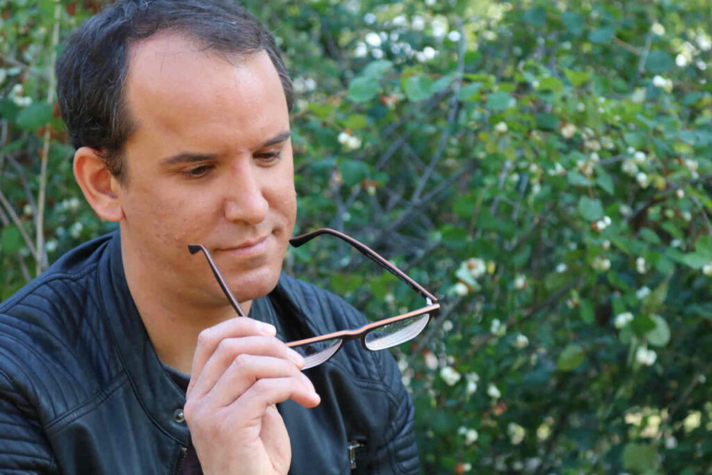 Ferdinand Saalbach hat seine Brille abgenommen, hält sie in der Hand und schaut sie an